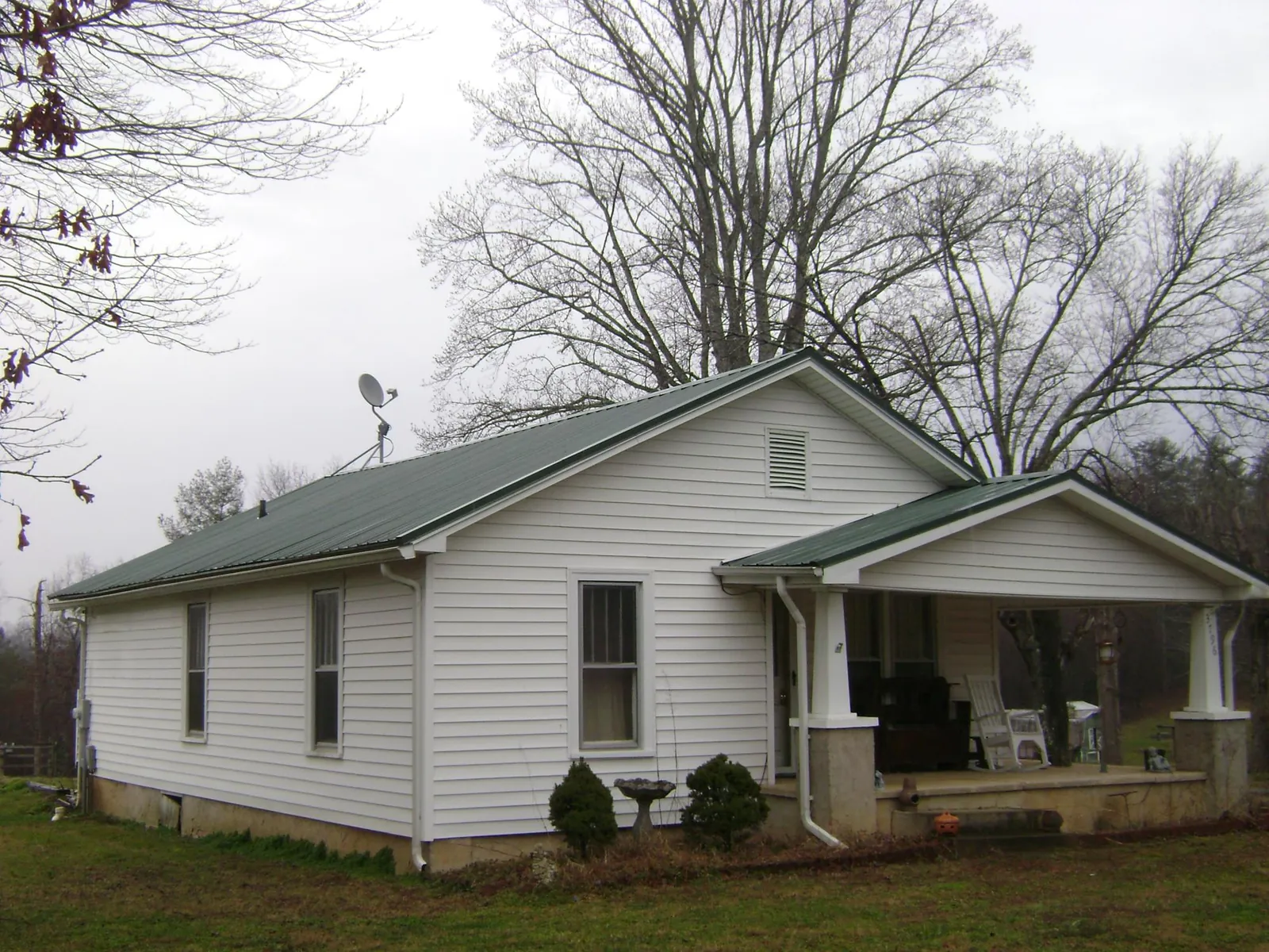 Green metal roof on a white bungalow with a side porch in Saratoga